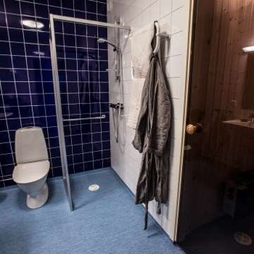 Bild på en toalett med duschhörn och toalettstol
